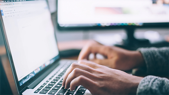 A person typing on an Apple Mac laptop; image used for blog post about claiming a refund for UBIT or adjusting Form 990-T