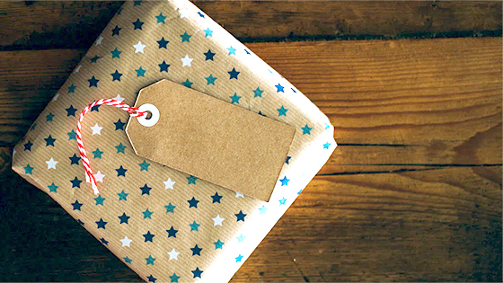 a small box wrapped in brown paper with blue and white starts on it sits on a wooden table; image used for a blog post about not-for-profits matching gifts to double donor contributions
