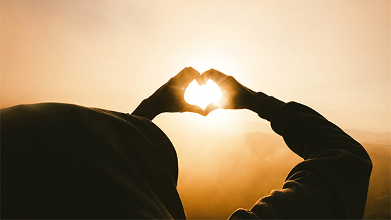 a person forming a heart with their hands against the sun; image used for blog post about how not-for-profits can handle gifts in kind and donated services during COVID-19 pandemic