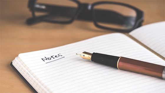 a pen sitting on top of a blank page of a journal with "notes" on top of the page; image used for a blog post about COVID-19 tax questions