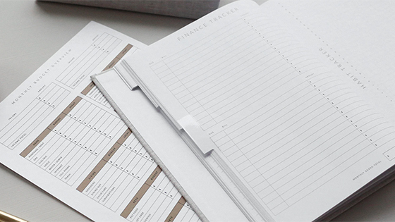 a blank financial tracker booklet sits on top of an expenses paper; image used for blog post about the 2021 Health Savings Accounts released by the IRS