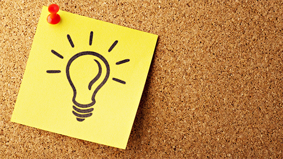 a yellow post-it note with a drawn light bulb pinned to a cork board; image used for blog post about thinking like an auditor for not-for-profit revenue opportunities