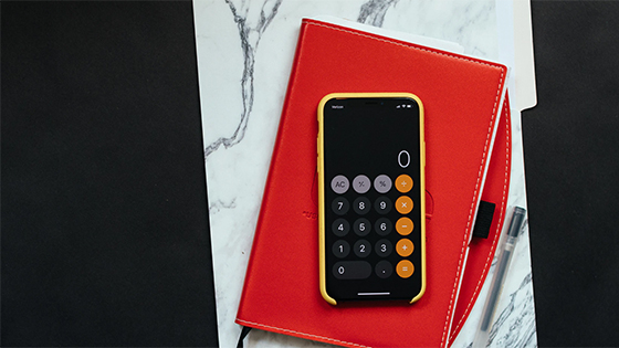 a phone calculator sitting on top of a red journal and white and grey folder; image used for blog post about paying tax on social security benefits