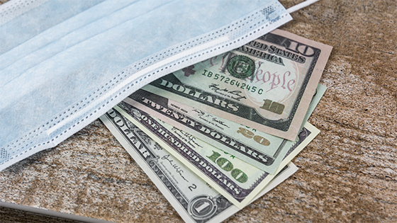 dollar bills sitting underneath a medical mask; image used for blog post about deferral of employees