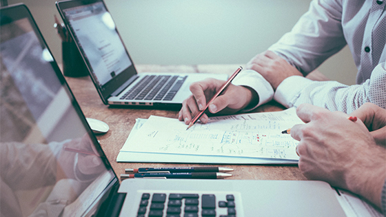 two businessmen writing on a document together; image used for blog post about using footnotes in a not-for-profit