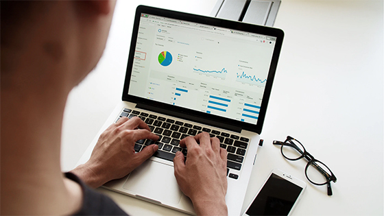 a woman typing on a laptop with data and graphs on screen; image used for blog post about not-for-profits reviewing accounting function