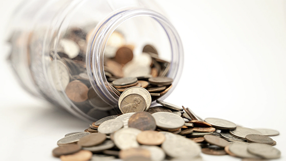 coins spilling out of a clear glass jar; image used for blog post about tax law changes impacting retirement savings