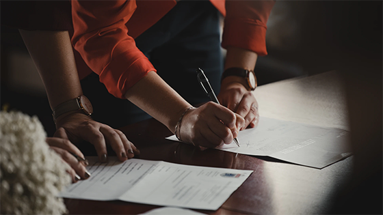 two people writing on a piece of paper on a table; image used for blog post about not-for-profit compliance with procurement policy after updates to Uniform Guidance