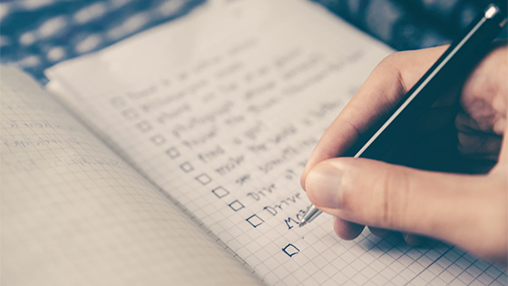 person writing in a notebook with check boxes; image used for blog post about not-for-profits preparing for an audit