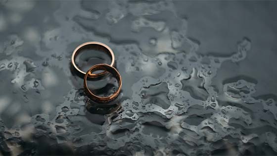 two rings sitting on the ground surrounded by rain drops; image used for blog post about tax implications for business owners going through divorce