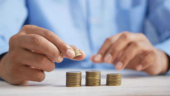 person in a button down shirt counting gold coins with their hands; image used for blog post with tips for not-for-profit loans