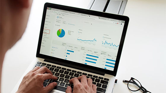 someone working on a laptop with a screen showing data and stats; image used for blog post about mitigating commission fraud