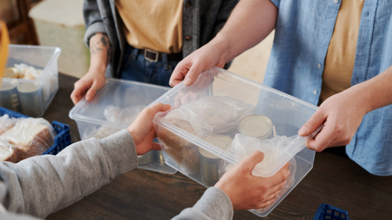 A photo of two people exchanging a bin of canned goods for charity donations; image used for blog post for not-for-profit quid pro quo reporting obligations