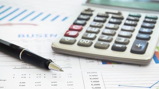 An image of a calculator and pen sitting on top of financial documents; image used for blog post about breaking not-for-profit bad budget habits