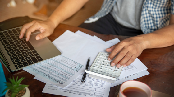 092922 – Tax Planning Ideas for Individuals’ Year-End – 560×315 An image of a person looking at tax documents and using a laptop; image used for blog post about individuals' year-end tax planning