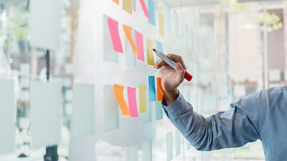 An image of a person holding a marker towards a board with color sticky notes; image used for blog post about not-for-profits regaining tax-exempt status