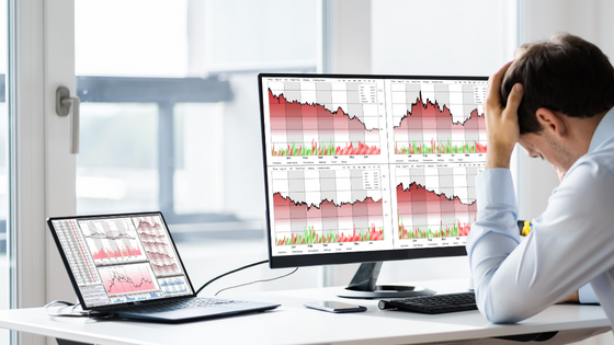 A photo of someone distressed sitting in front of computer screens with declining financial data with a palm against the forehead; image used for blog post about accounting standard affecting not-for-profits