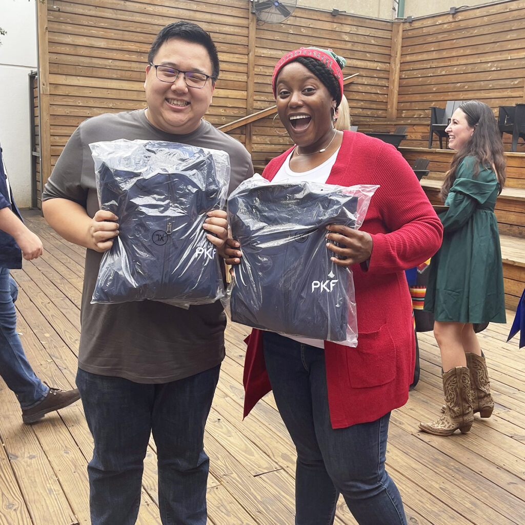 Photo of PKF Texas team members holding packaged jackets at a firm event