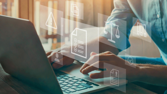 An image of a person typing on a laptop with hologram images of documents and balances; for blog post about not-for-profit compliance