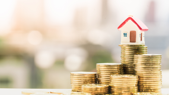 Photo of a tiny house sitting on top of stacks of coins; for blog post about inherited assets